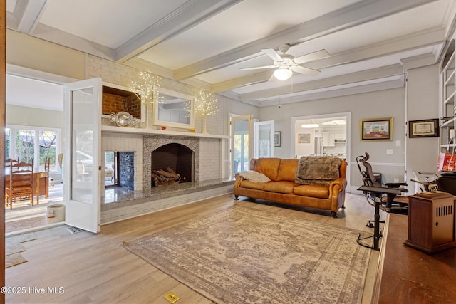 living area with a healthy amount of sunlight, a brick fireplace, wood finished floors, and beamed ceiling