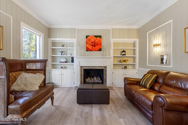 living area featuring a fireplace, wood finished floors, built in features, and crown molding