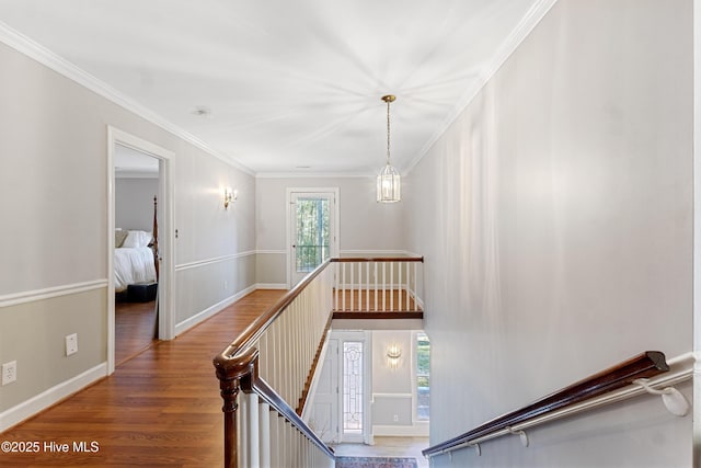 corridor featuring ornamental molding, baseboards, an upstairs landing, and wood finished floors