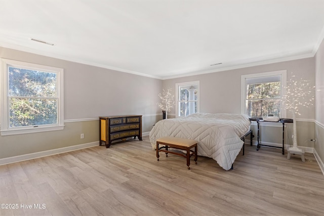 bedroom featuring ornamental molding, multiple windows, light wood-type flooring, and visible vents