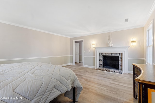 bedroom featuring visible vents, baseboards, ornamental molding, wood finished floors, and a brick fireplace