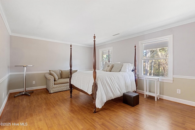 bedroom featuring light wood-style floors, visible vents, crown molding, and baseboards