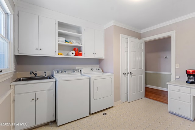 washroom with cabinet space, independent washer and dryer, crown molding, light floors, and a sink