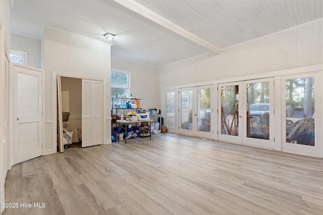 interior space with crown molding, beam ceiling, wood finished floors, and french doors