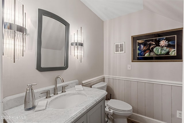 bathroom featuring visible vents, toilet, a wainscoted wall, vaulted ceiling, and vanity