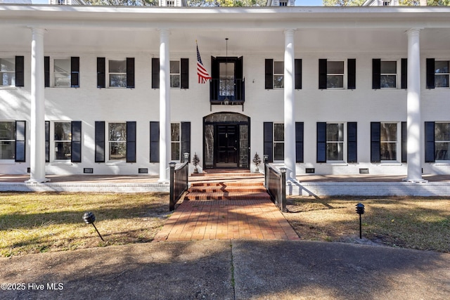 neoclassical / greek revival house with a balcony and brick siding