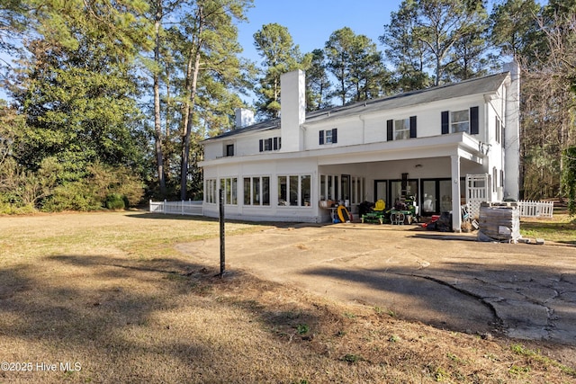 back of house with a chimney and a lawn