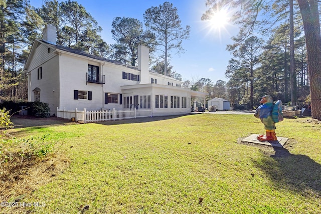 back of property featuring a sunroom, a lawn, a chimney, and fence