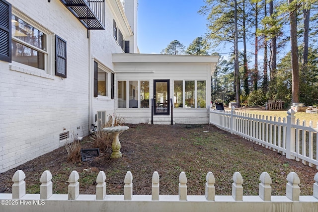 exterior space featuring central AC, fence, and a sunroom