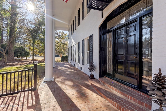 view of exterior entry featuring a porch and brick siding