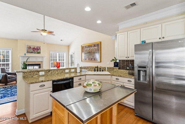 kitchen featuring visible vents, dishwasher, stainless steel fridge with ice dispenser, a peninsula, and a sink