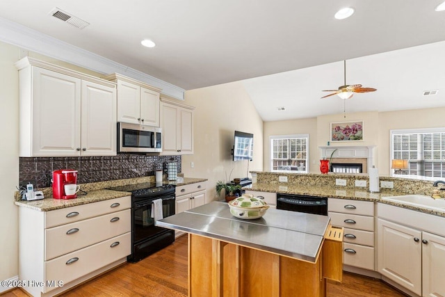 kitchen with light wood finished floors, visible vents, decorative backsplash, black appliances, and a sink