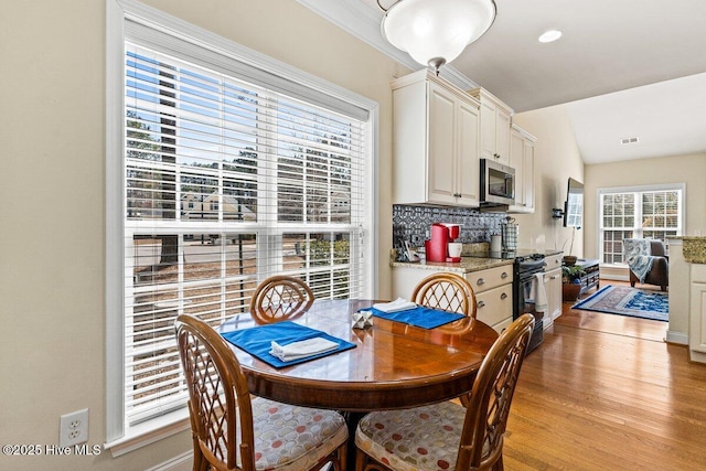 dining room featuring light wood-type flooring, visible vents, and lofted ceiling