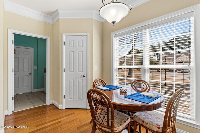 dining room with ornamental molding, light wood-type flooring, and baseboards