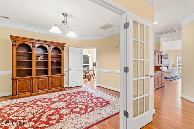 interior space with a notable chandelier, visible vents, wood finished floors, and ornamental molding