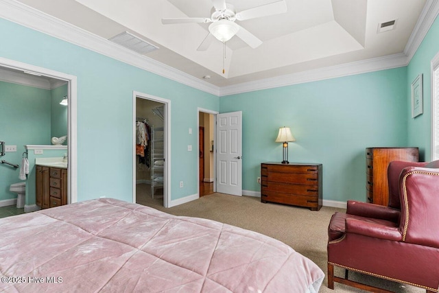 bedroom featuring a raised ceiling, carpet floors, a walk in closet, and visible vents