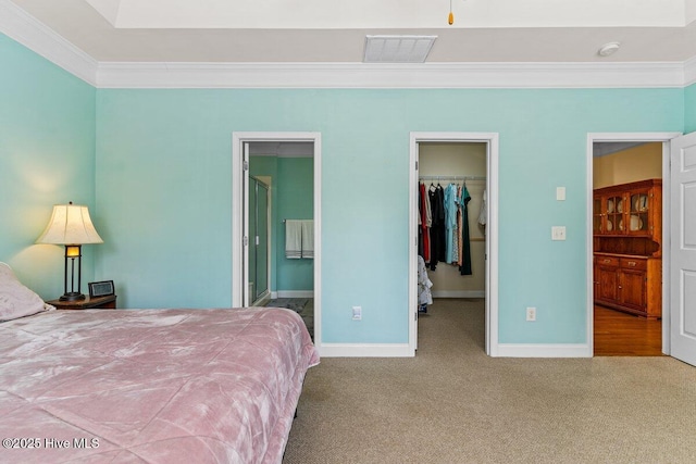 carpeted bedroom featuring visible vents, baseboards, a spacious closet, ornamental molding, and a closet