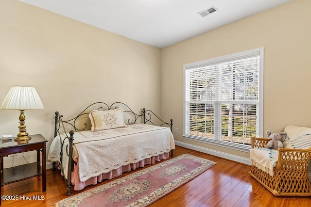 bedroom featuring wood finished floors, visible vents, and baseboards