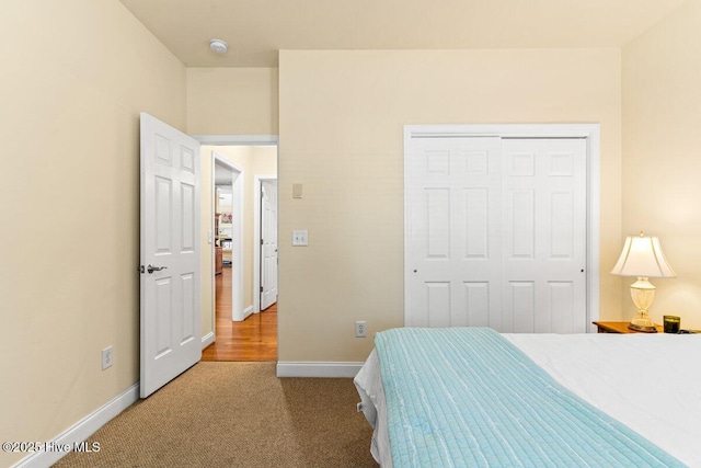 carpeted bedroom with a closet and baseboards