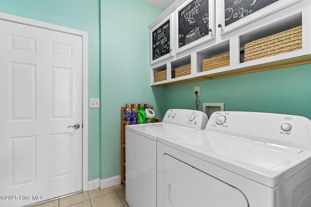 laundry area with light tile patterned floors, washing machine and dryer, baseboards, and cabinet space