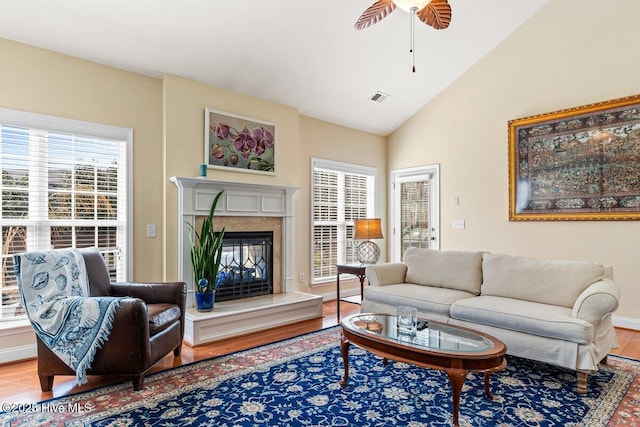 living area featuring lofted ceiling, a premium fireplace, wood finished floors, and visible vents