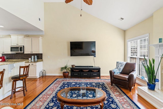 living area with light wood-type flooring, visible vents, and baseboards