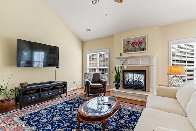 living room with vaulted ceiling, a premium fireplace, wood finished floors, and a healthy amount of sunlight