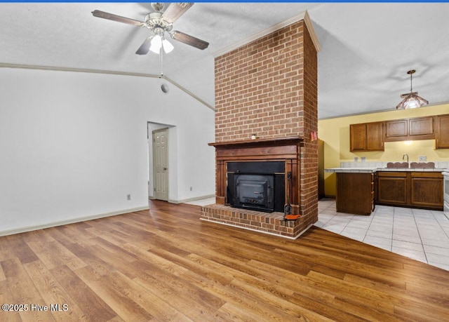 5200 Pineview Rd, Lumberton, NC 28360 - unfurnished living room featuring a ceiling fan, light wood-style floors, vaulted ceiling, a fireplace, and baseboards