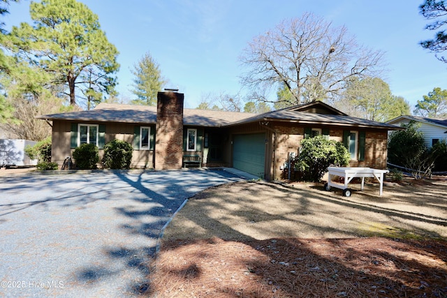 single story home featuring a garage, driveway, a chimney, and brick siding