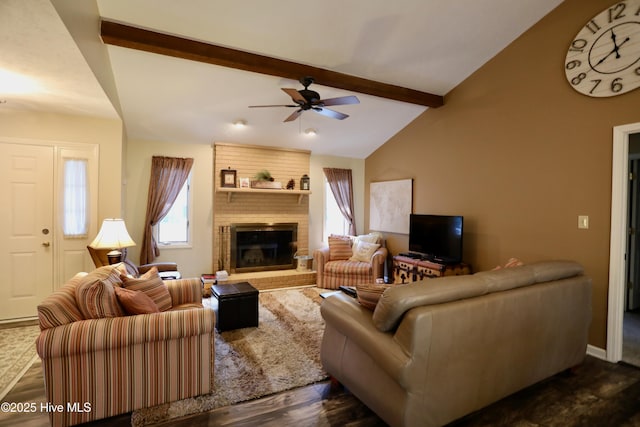 living area featuring vaulted ceiling with beams, dark wood-type flooring, a fireplace, and a ceiling fan