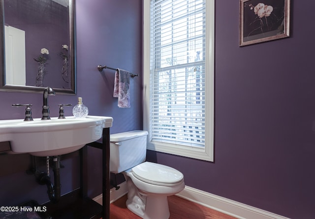 bathroom featuring toilet, baseboards, a sink, and wood finished floors