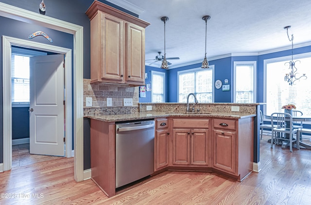 kitchen with a sink, light wood finished floors, a peninsula, and dishwasher