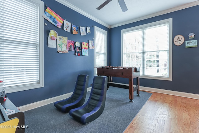 game room featuring baseboards, plenty of natural light, ornamental molding, and wood finished floors