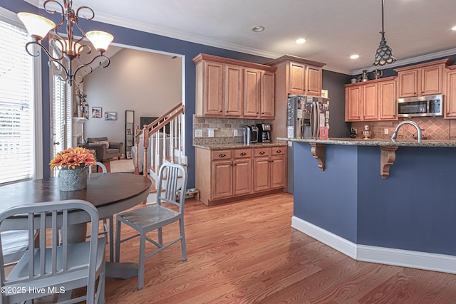 kitchen with light stone counters, stainless steel appliances, light wood-type flooring, a kitchen bar, and crown molding