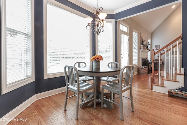 dining room with light wood-type flooring, a fireplace, baseboards, and stairs