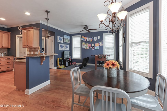 dining area with a wealth of natural light, light wood-style flooring, and crown molding