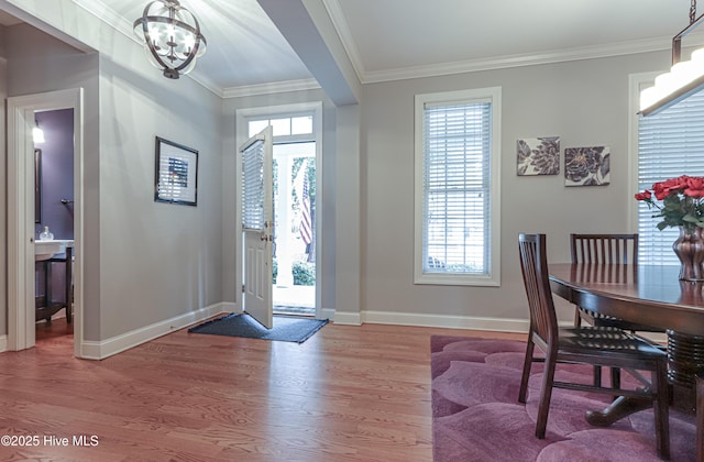 foyer entrance featuring ornamental molding, a notable chandelier, baseboards, and wood finished floors