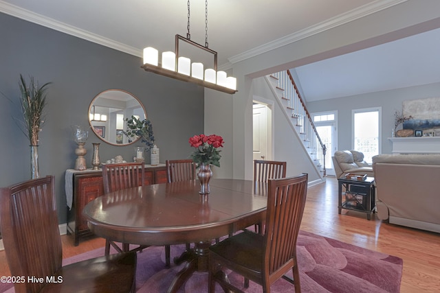 dining space with stairs, baseboards, wood finished floors, and crown molding