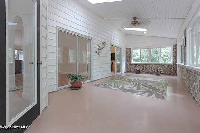 sunroom / solarium with concrete floors, arched walkways, and vaulted ceiling with skylight