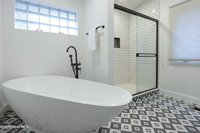 full bath featuring a stall shower, a soaking tub, and baseboards