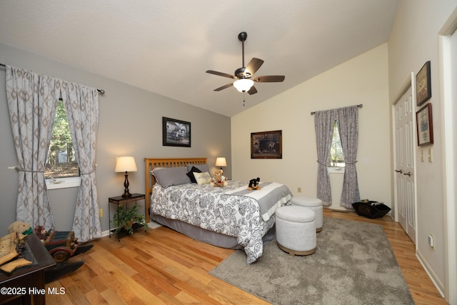 bedroom with ceiling fan, light wood-style flooring, and vaulted ceiling