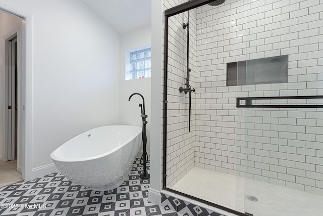 full bath with tile patterned floors, a freestanding bath, a stall shower, and baseboards