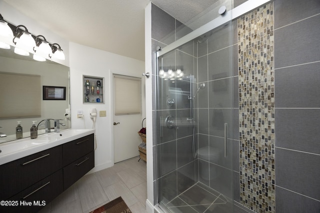 full bath featuring double vanity, a stall shower, and a sink