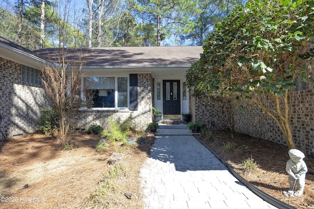 doorway to property featuring brick siding