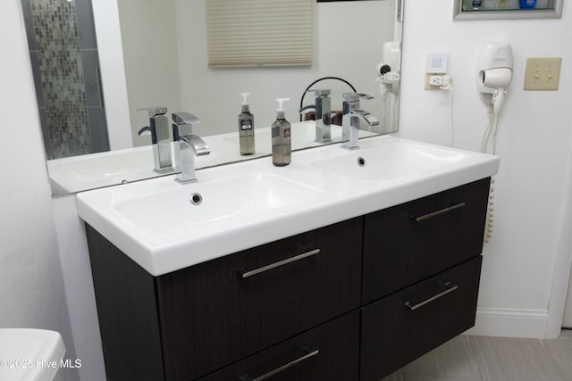 full bath featuring double vanity, a sink, and toilet