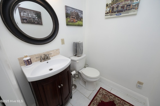 half bathroom with toilet, vanity, and baseboards