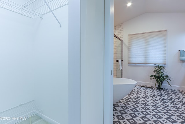 bathroom featuring a soaking tub, baseboards, vaulted ceiling, tile patterned floors, and a shower with shower door
