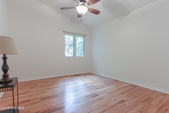 empty room with lofted ceiling, light wood-style floors, ceiling fan, visible vents, and baseboards