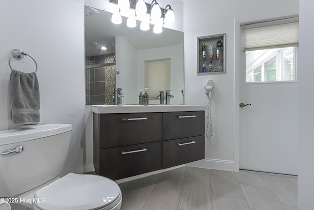 full bathroom featuring baseboards, tiled shower, toilet, and vanity
