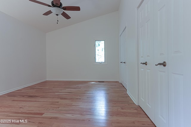 unfurnished bedroom featuring ceiling fan, baseboards, lofted ceiling, and light wood-type flooring